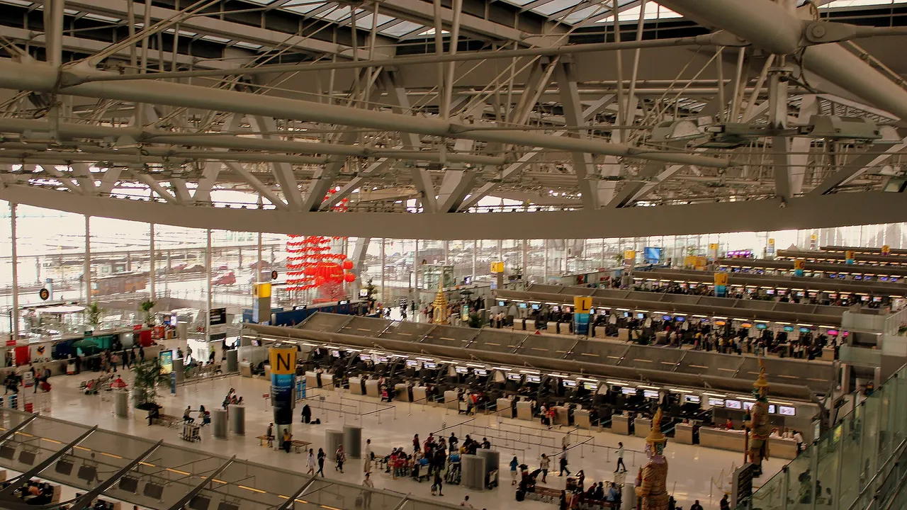 Alignement de comptoirs d’enregistrement sous un large tableau des départs dans un hall d’aéroport.