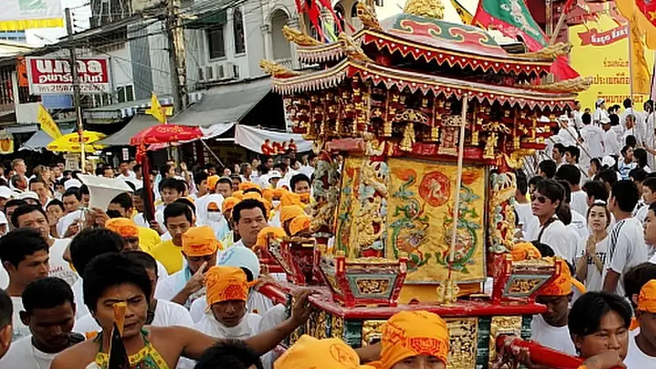 Die Sänfte der Gottheit, von weiß gekleideten Gläubigen durch die Straße getragen, beim Vegetarierfestival in Phuket